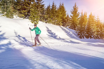 Woman snowboarding during sunny day