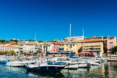 Sailboats moored at harbor against clear blue sky