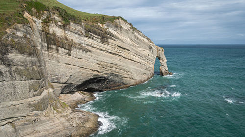 Rock formation in sea against sky