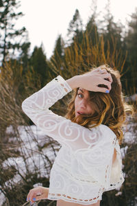 Woman standing by tree trunk in winter