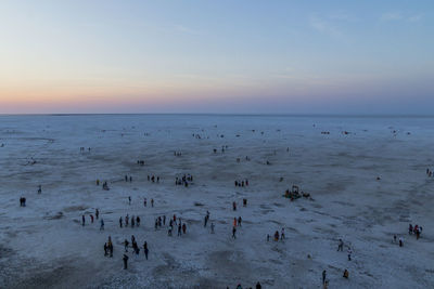 High angle view of people on beach against sky during sunset