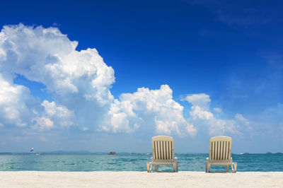 Deck chairs on beach against sky