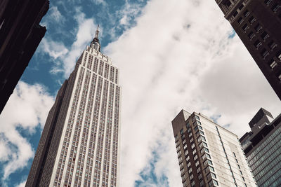 Low angle view of modern buildings against cloudy sky