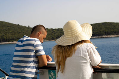 Rear view of man and woman wearing hat against sky