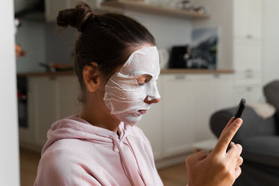 Close-up of woman wearing face mask using mobile