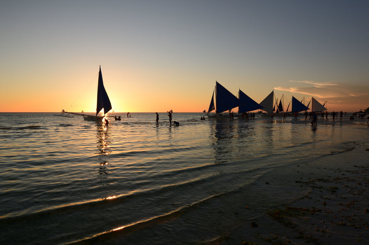 SILHOUETTE SAILBOATS ON SEA AGAINST ORANGE SKY