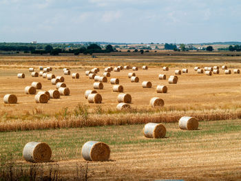 Hay bales on field against sky