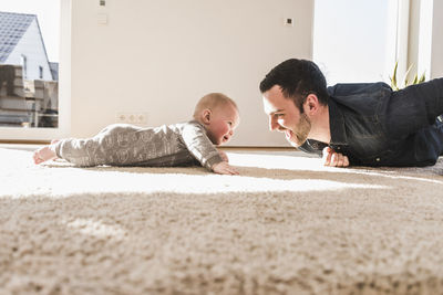 Father and baby son playing crawling on carpet