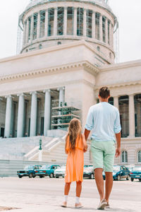 Rear view of man and woman walking on building