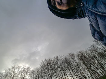 Low section of man by tree against sky