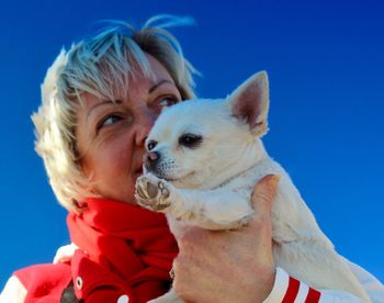 Woman with dog looking away against clear blue sky