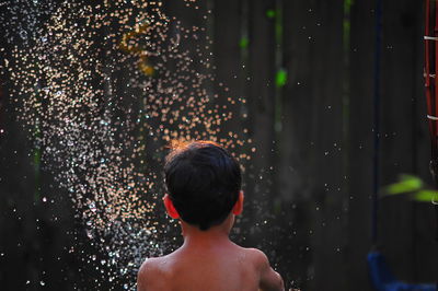 Rear view of shirtless boy in water