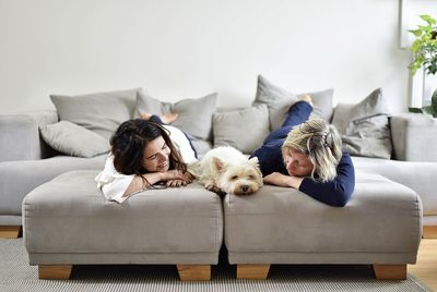 Mother and daughter relaxing with dogs relaxing on sofa at home