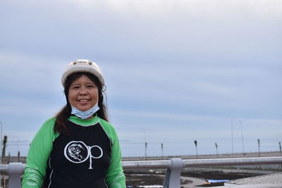 Portrait of smiling young woman standing against sky