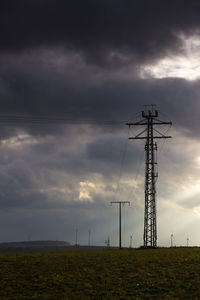 Low angle view of electricity pylon on field against sky