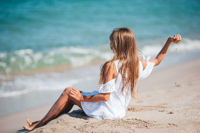 Rear view of woman sitting at beach