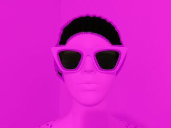 Close-up of woman wearing sunglasses against pink background