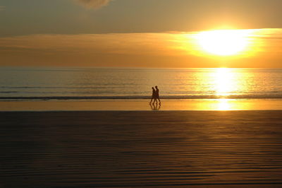 Silhouette man on beach against sky during sunset
