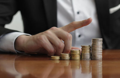 Cropped image of hand holding stack of coins on table