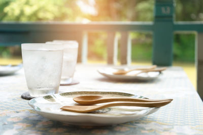 Forks and spoons on plates by drinking glass on table at porch