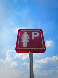 Low angle view of pink sign of reserved parking area for ladies against cloudy sky