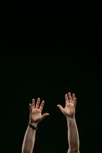 Low angle view of people hands against black background