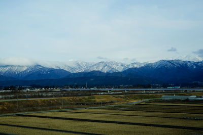 Scenic view of field and snowcapped mountains against sky