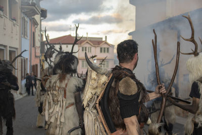 Rear view of people on street amidst buildings in city