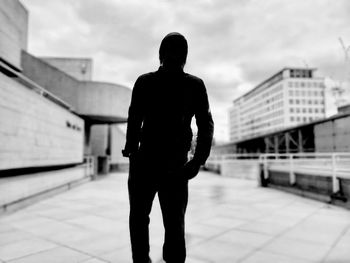 Rear view of silhouette man standing against sky in city