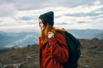 Young woman looking at camera against sky