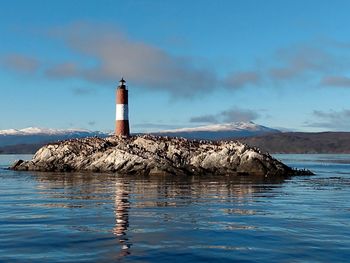 Lighthouse on building by sea against sky