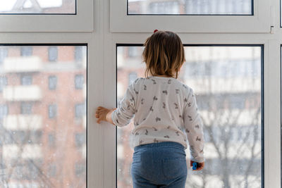 Rear view of woman looking through window