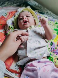 Cropped image of woman holding baby girl hand sleeping on bed