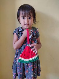 Portrait of cute girl standing against wall