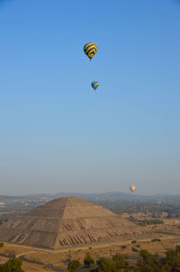 Hot air balloon flying over sea against clear sky