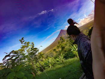 Side view of woman standing against mountain and sky