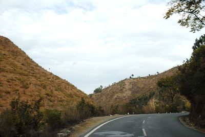 Road amidst trees against sky