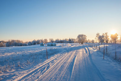 Snow covered field against clear sky