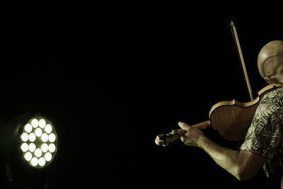 Man playing guitar against black background