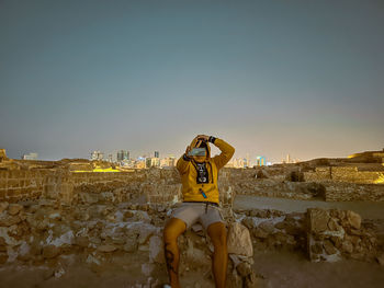 Rear view of woman with arms outstretched standing against clear sky