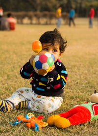 Full length of boy with toys sitting on field