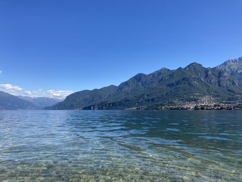 Scenic view of sea and mountains against clear blue sky