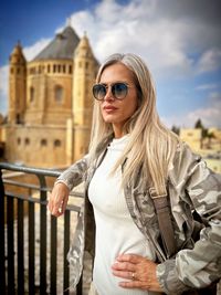 Portrait of young woman wearing sunglasses while standing in city