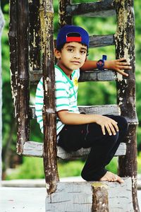 Portrait of boy sitting on tree trunk