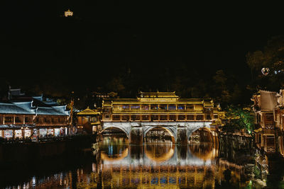 Illuminated bridge over river at night