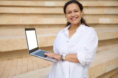 Portrait of young businesswoman using laptop while sitting on table