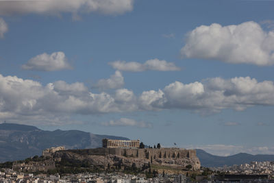 Buildings in city against cloudy sky