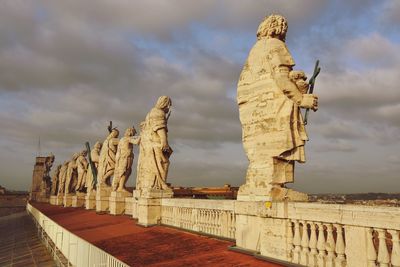 Statues at st peter basilica against cloudy sky