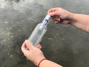 Cropped hand removing message from glass bottle