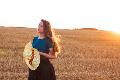 Adorable young girl in summer wheat field in straw hat. woman with long hair countryside sunset